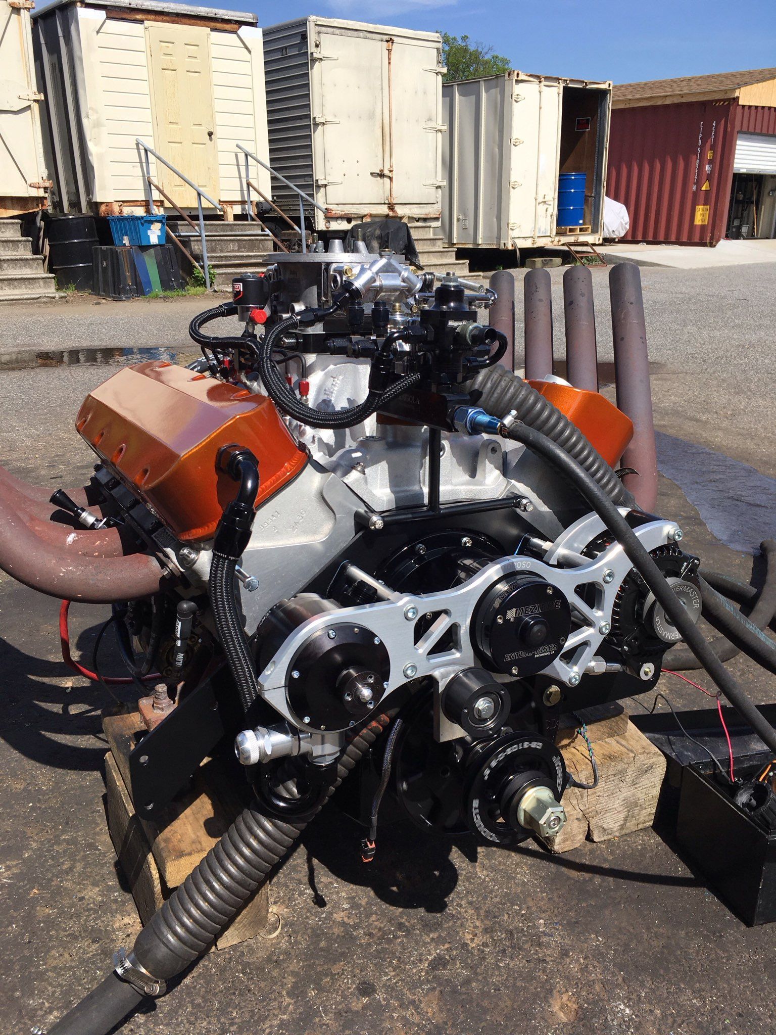 A large engine is sitting on top of a rock in a parking lot.