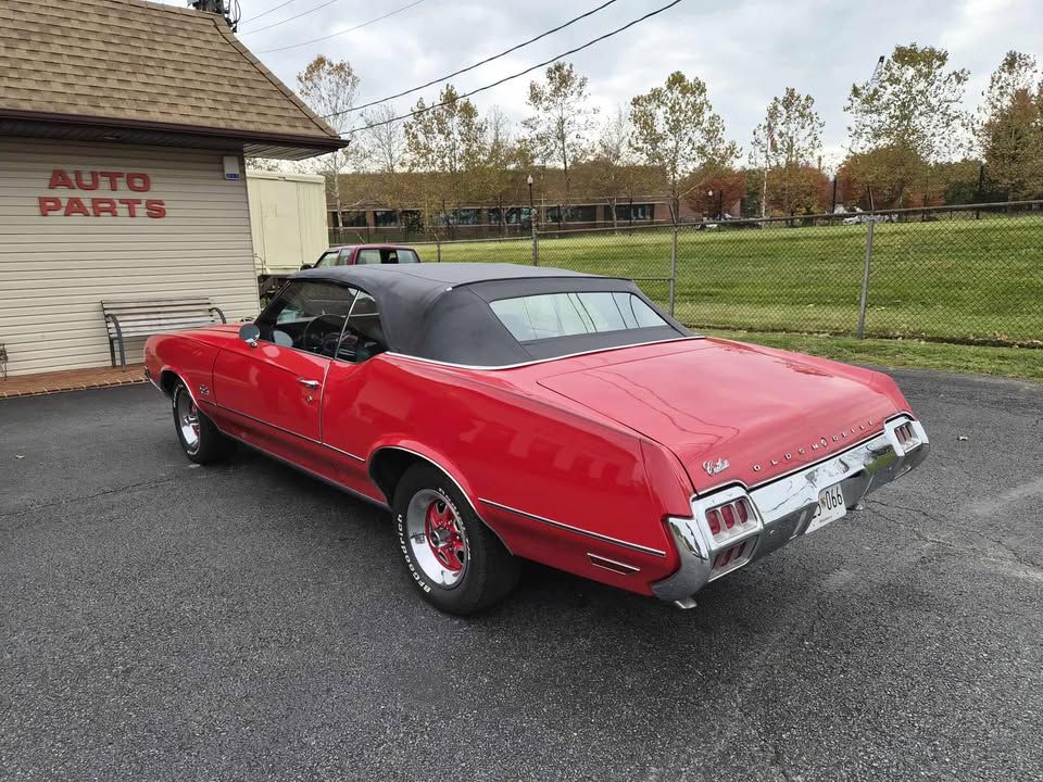 Red convertible car parked in front of an auto parts store.