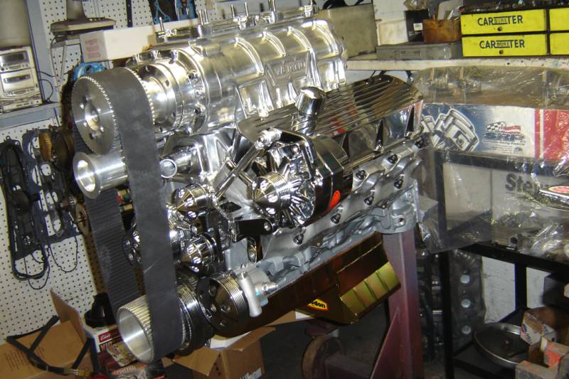 Shiny chrome engine with supercharger on a stand in a workshop.