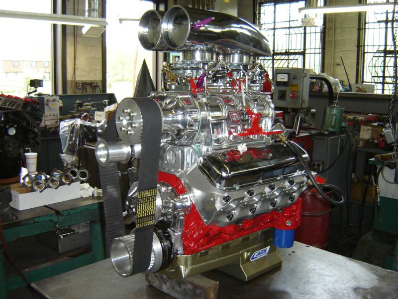 Chrome-covered, red engine with large air intakes, sitting on a metal table in a workshop.