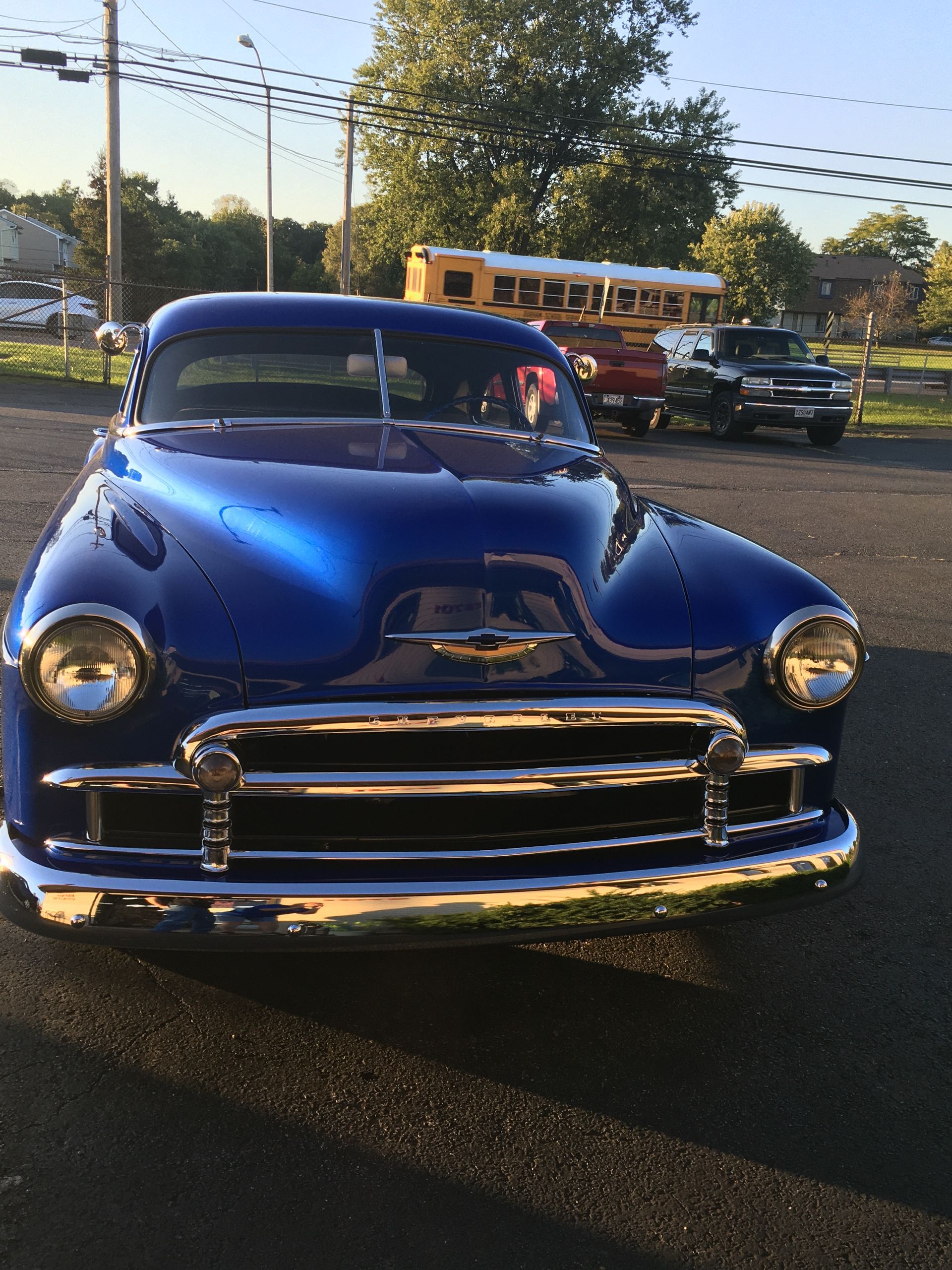 Blue classic Chevrolet car parked outdoors, sunlight highlighting chrome and body.