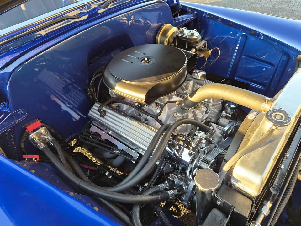 Blue classic car engine, detailed chrome components, black air filter.