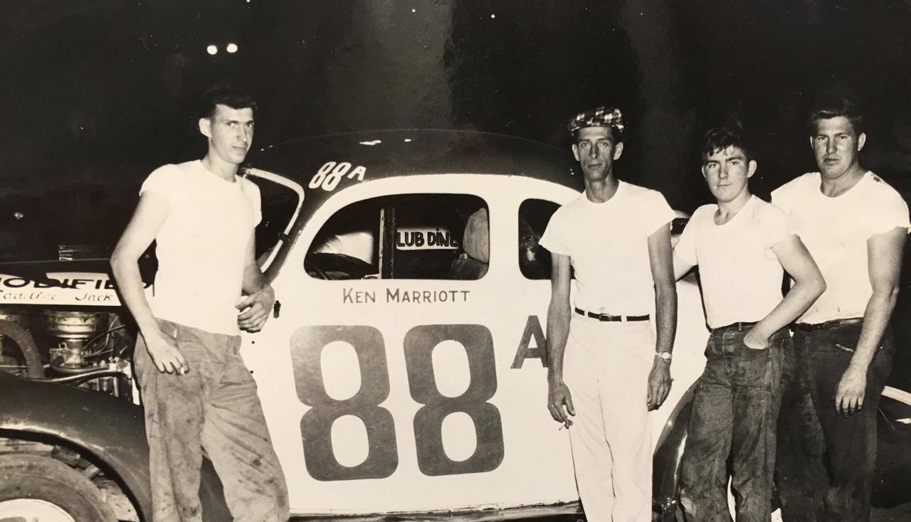 Five men stand in front of race car number 88. They appear to be at a racetrack, possibly the pit area.