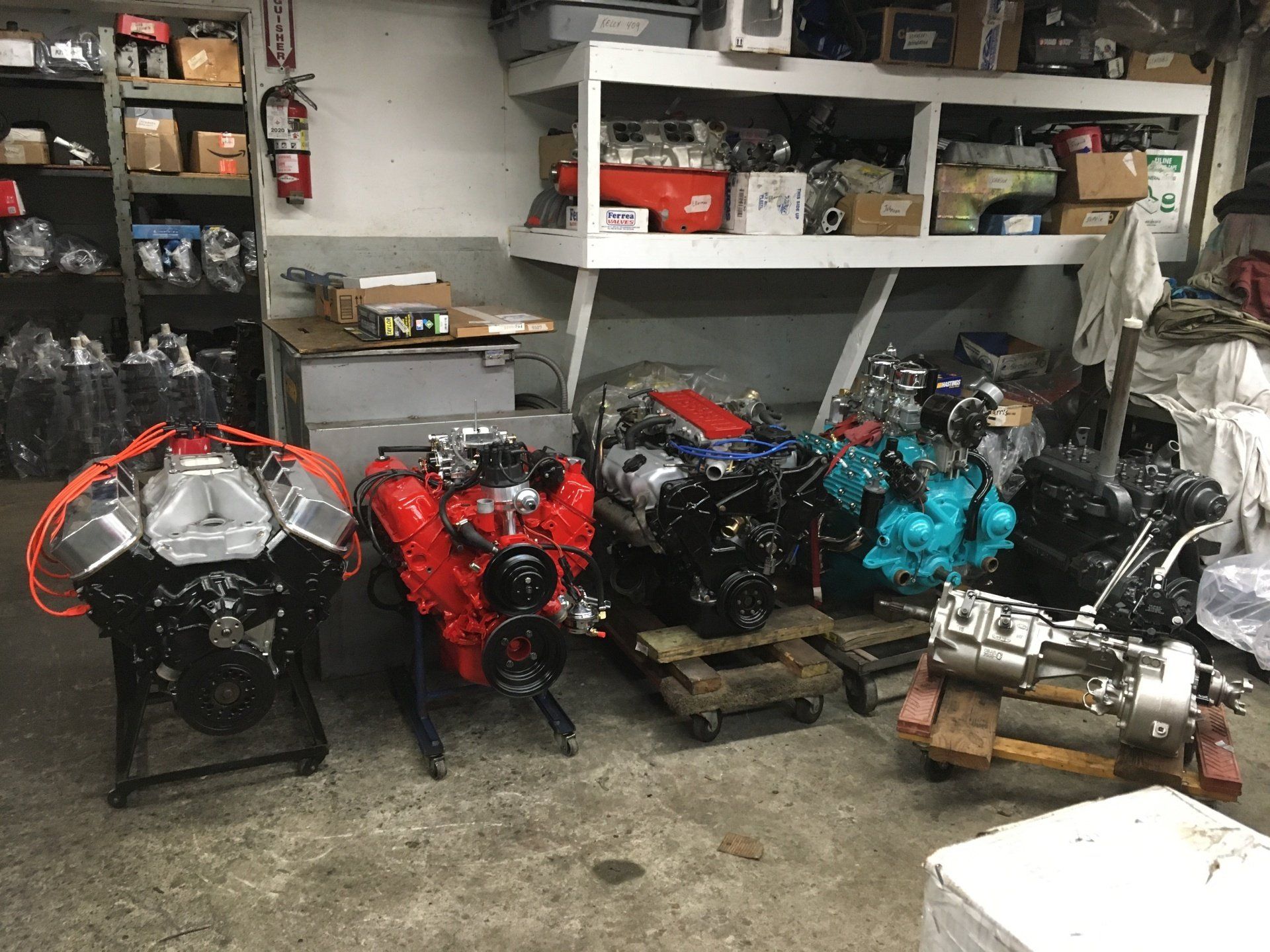 Several car engines, varying colors, in a workshop setting.
