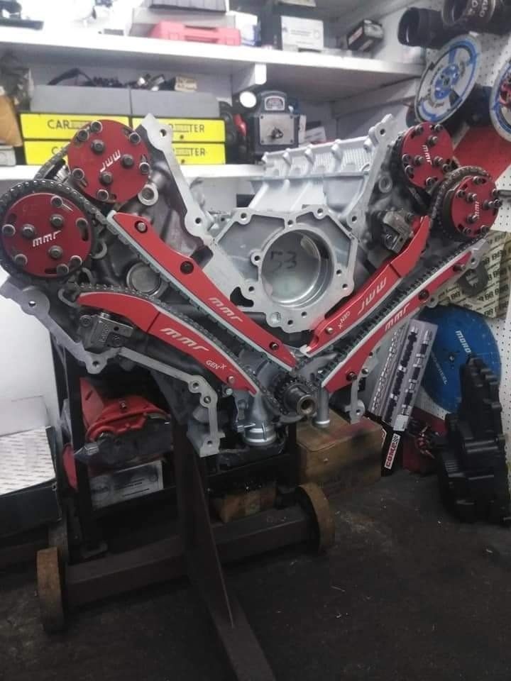Silver engine with red timing components, on a stand in a shop.