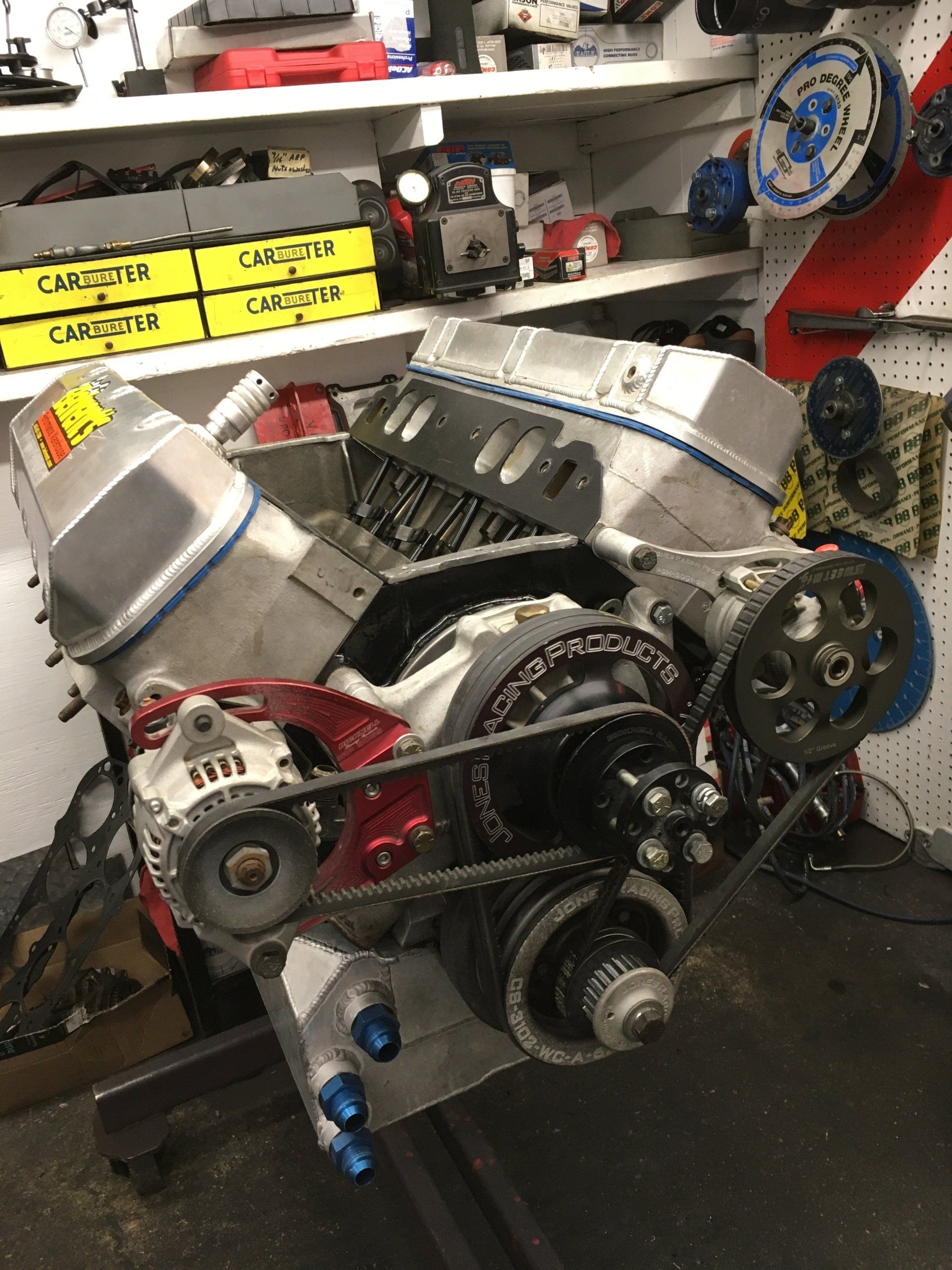 High-performance engine with silver components, black belts, and red accents in a workshop.