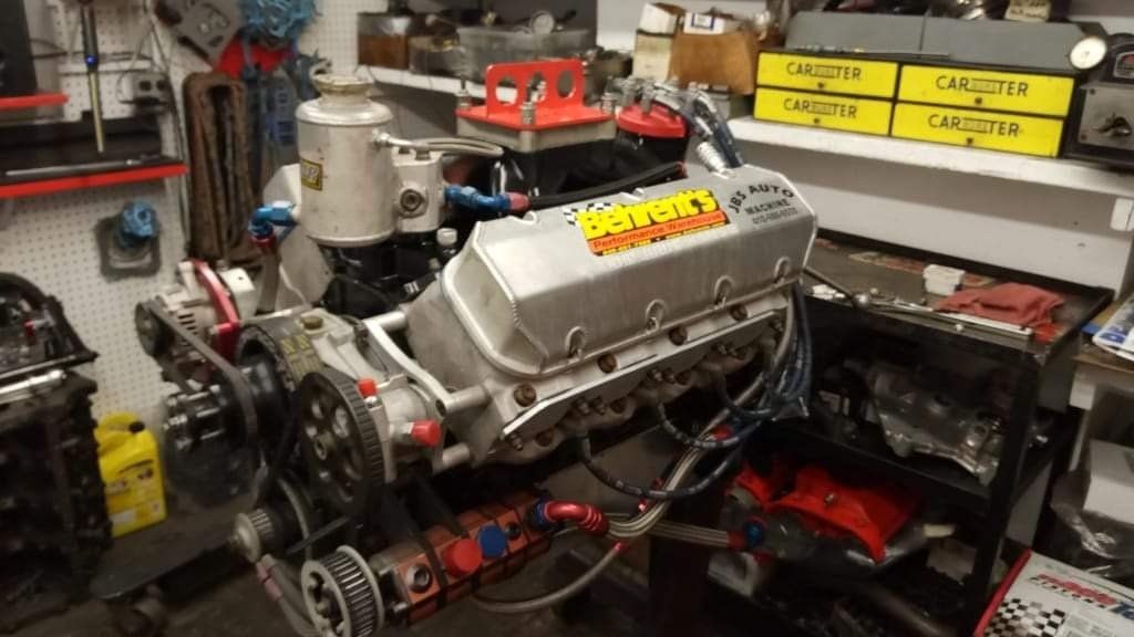 Engine block in a garage, with multiple pulleys and accessories, labeled 