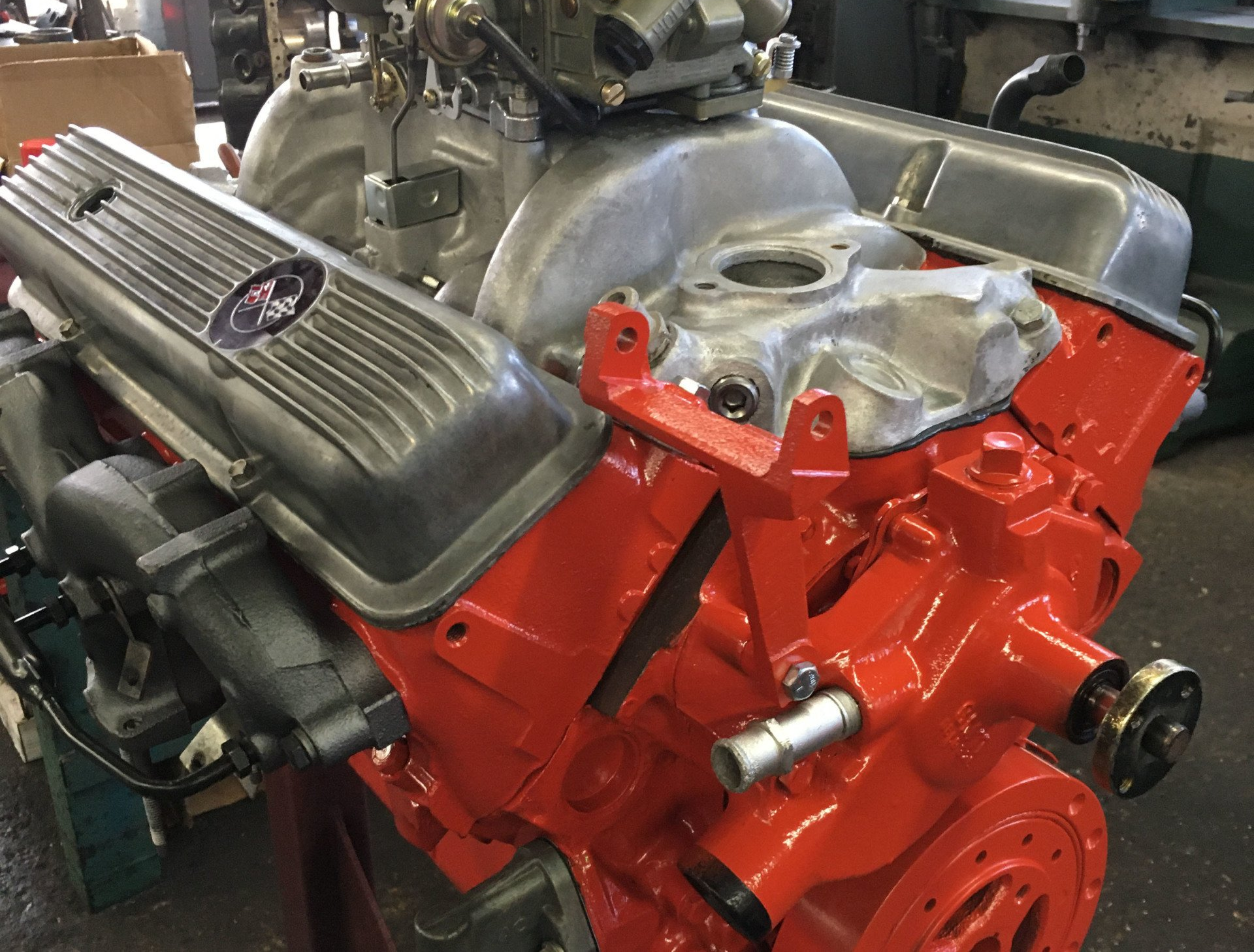 Red and gray Chevy engine, partially assembled, on a stand.