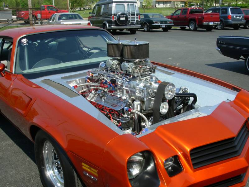 Orange classic car with an exposed, powerful engine.