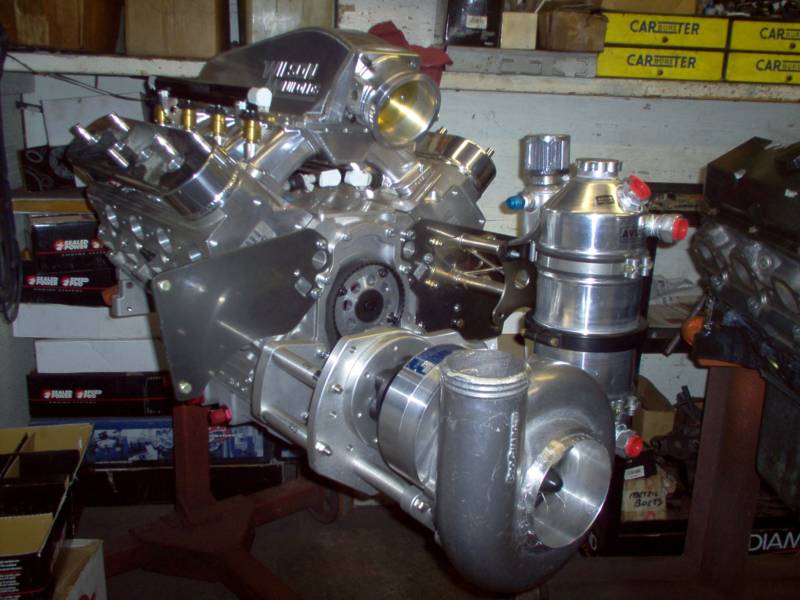 High-performance engine, silver with turbocharger, on a stand. Seen in a workshop setting.