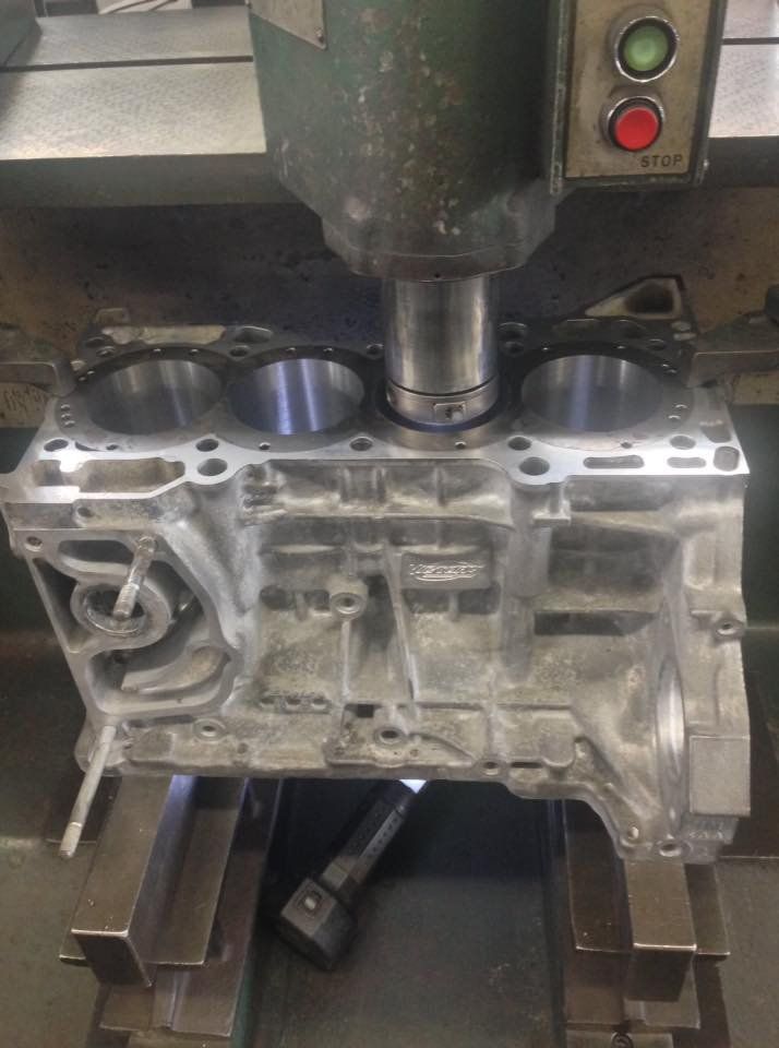 Engine block being machined by a vertical milling machine in a workshop.