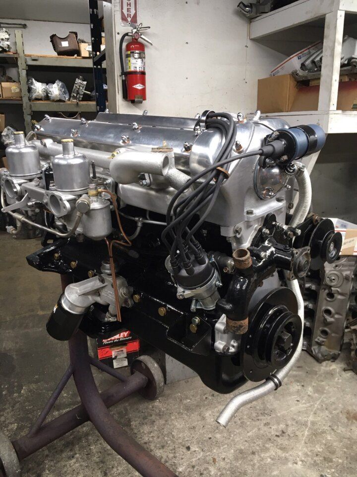 Restored black and silver Jaguar engine on a stand.