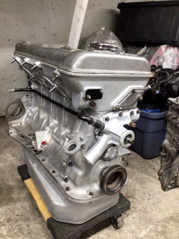 Silver engine on a black base in a workshop, awaiting installation.