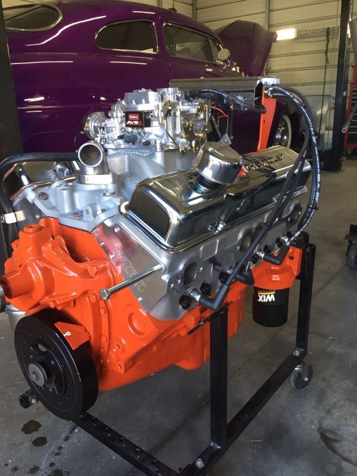 Orange and silver engine on a stand with a purple car in the background.