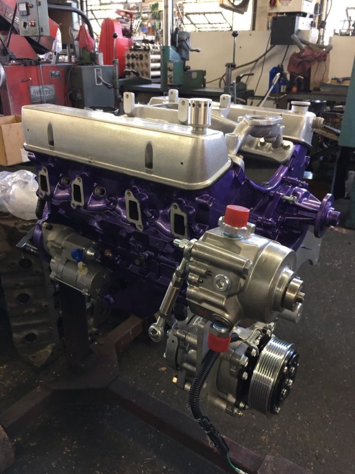 Purple and silver engine, with attached machinery, in a workshop setting.
