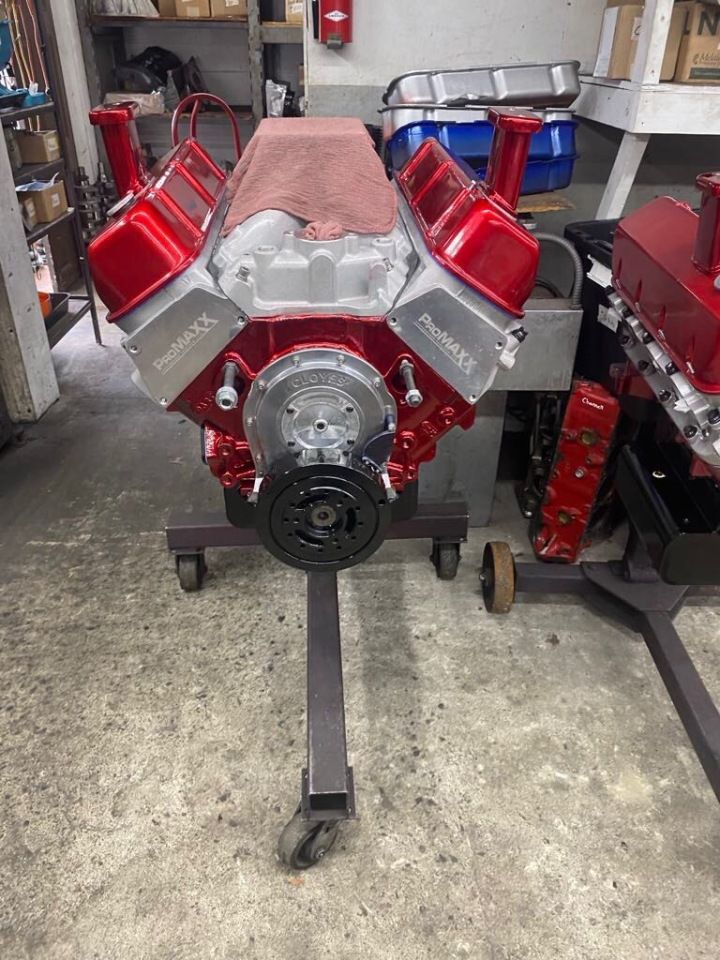 Red and silver engine on a stand in a garage. A second engine is partially visible on the right.