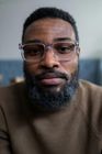 A man with a beard and glasses is looking at the camera.