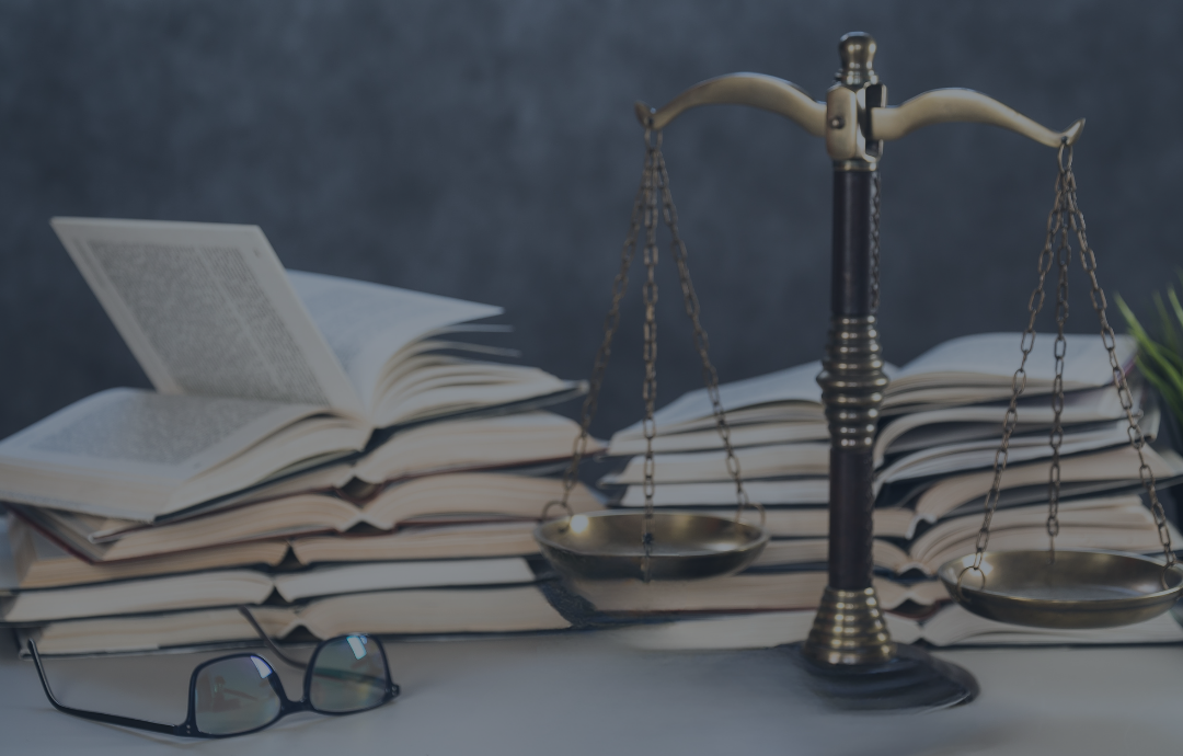 Two people shaking hands over a desk with a laptop and documents near a window.