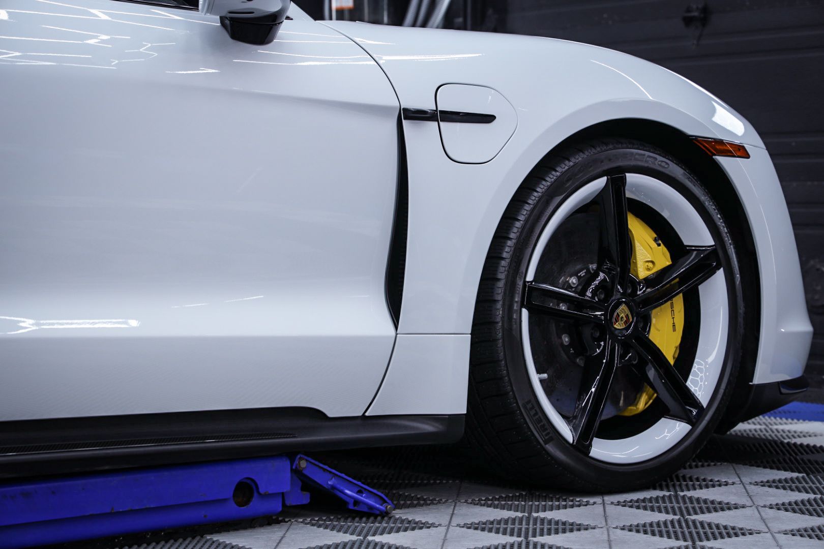 A white sports car is sitting on top of a blue lift.