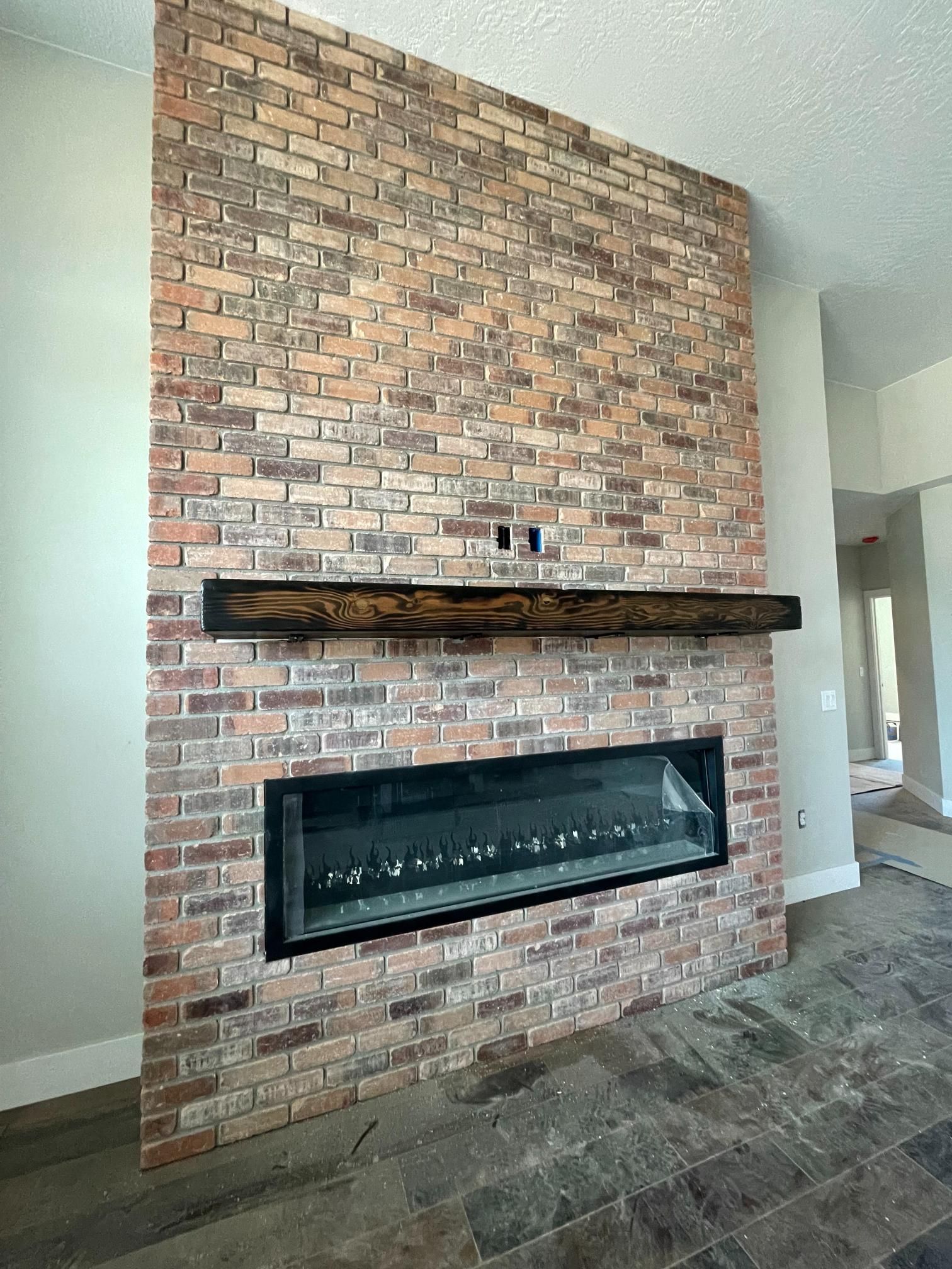 Brick fireplace with dark wood mantel and long, black-framed firebox.