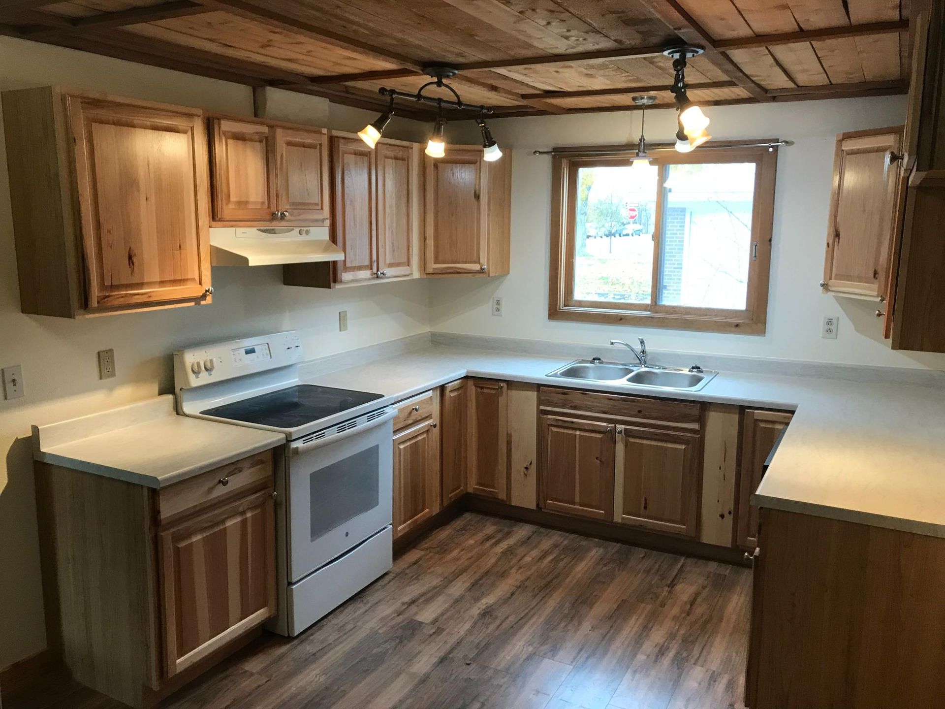Kitchen with wood cabinets, white appliances, and a wood ceiling and floor.