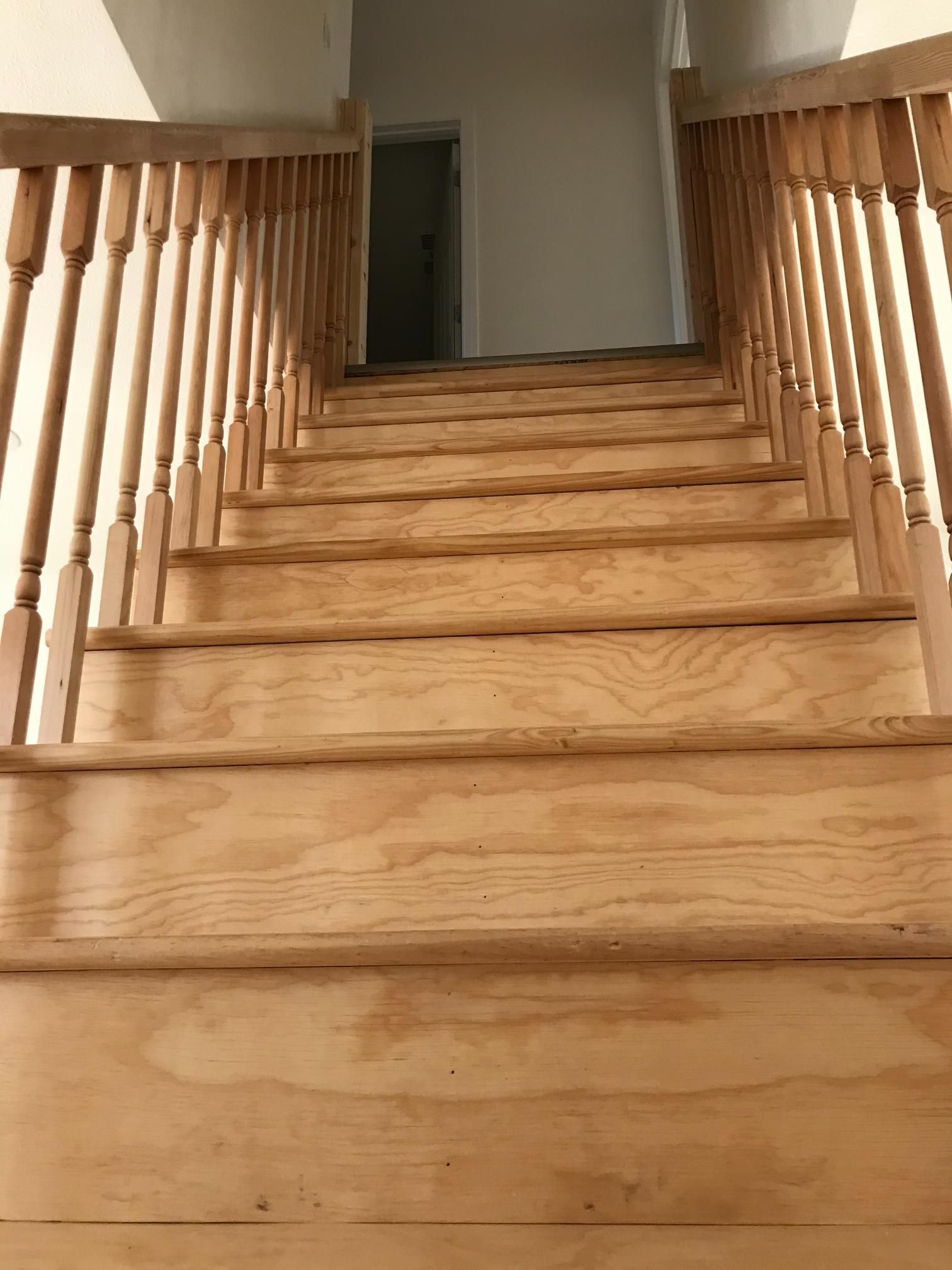 Wooden staircase leading upwards, with railings on both sides.