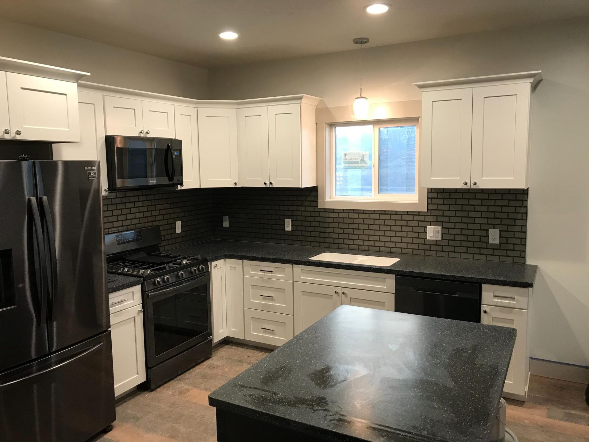 White kitchen cabinets, black appliances, dark countertops, and a black tiled backsplash.