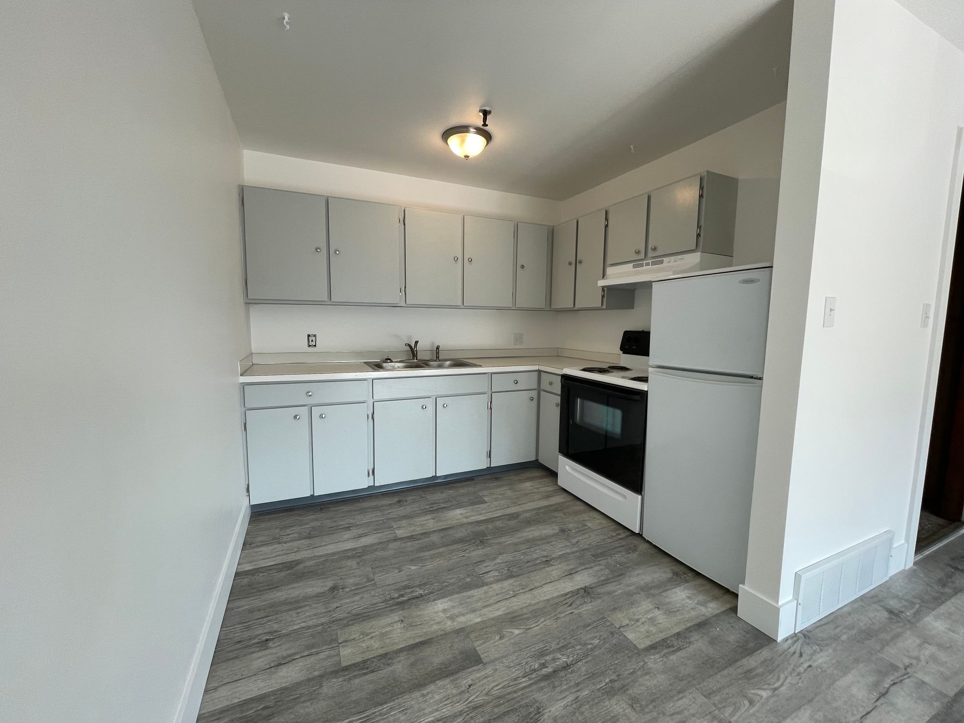 Kitchen with light gray cabinets, white appliances, and gray flooring.