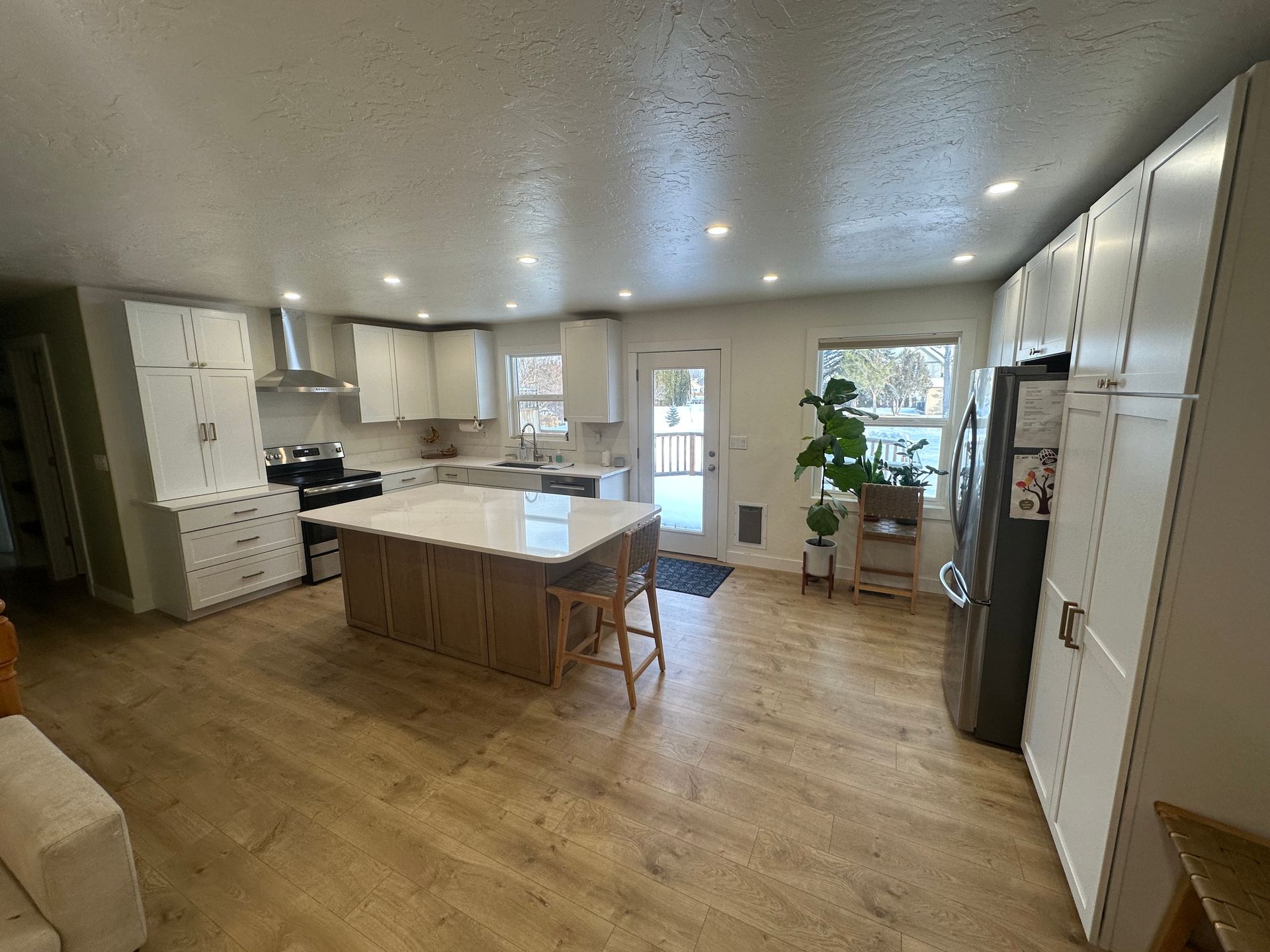 Bright kitchen with white cabinets, wood island, stainless steel appliances, and wood-look flooring.