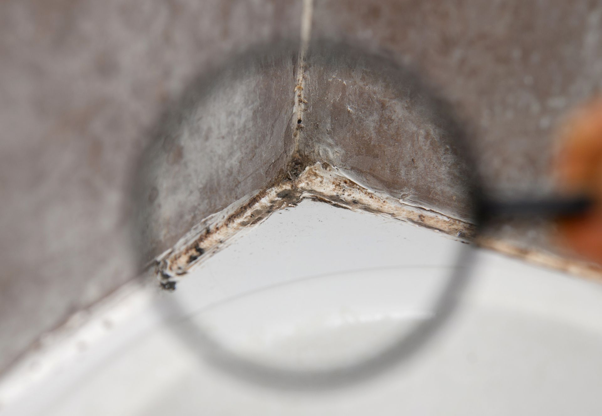 A person is looking at a corner of a wall with a magnifying glass.