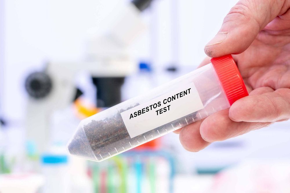 A person is holding a test tube with asbestos content in it.