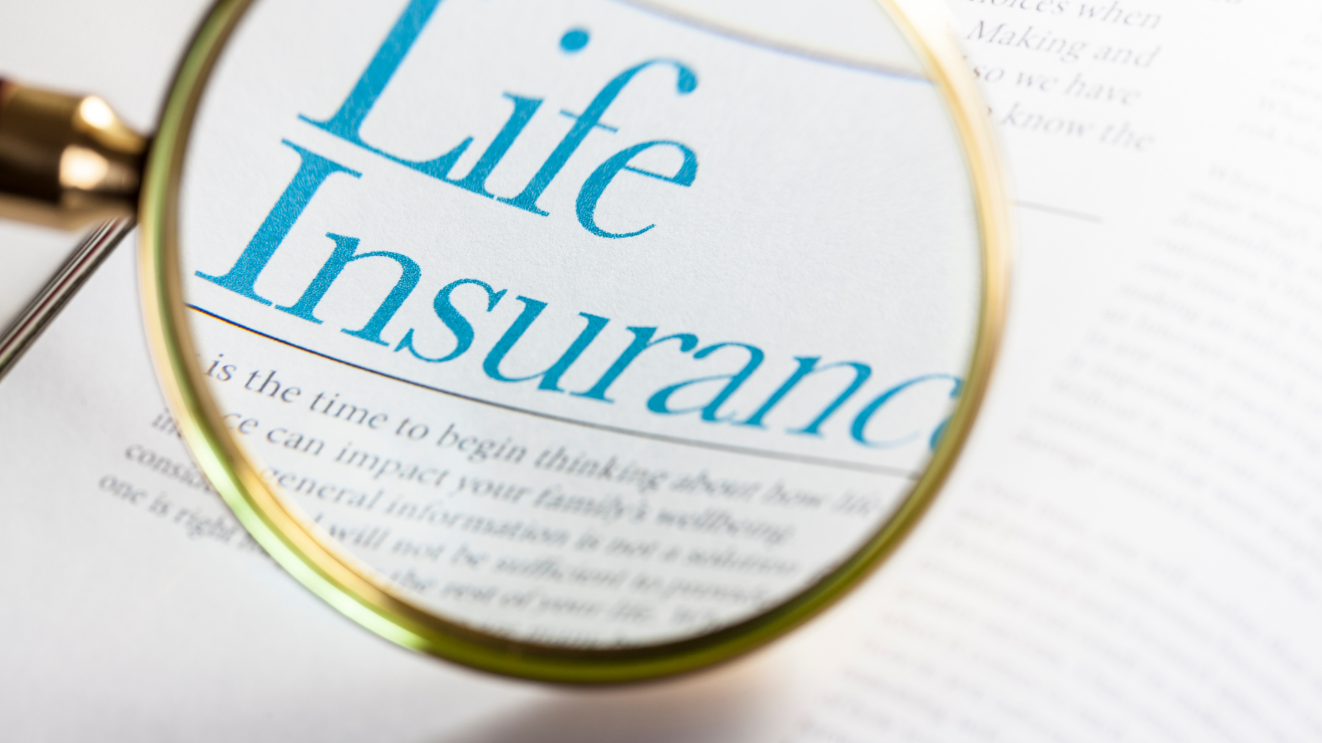 A magnifying glass is on a piece of paper that says life insurance