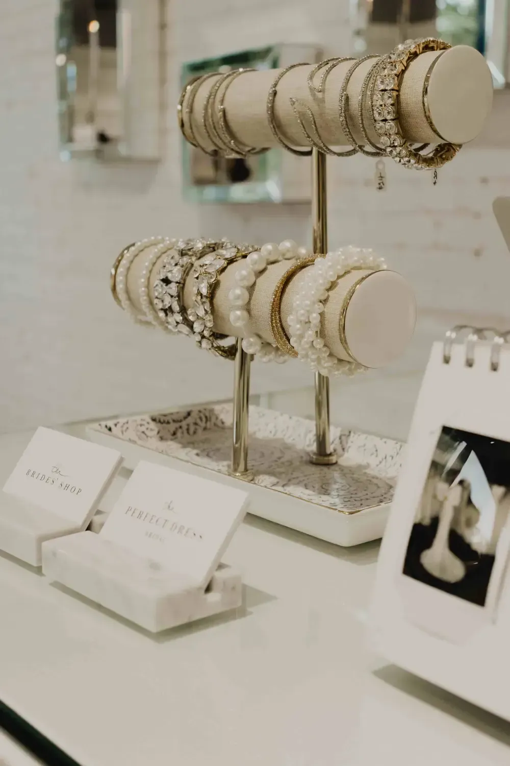 Bracelets displayed on a tiered stand, in a jewelry store setting. White and gold tones dominate.
