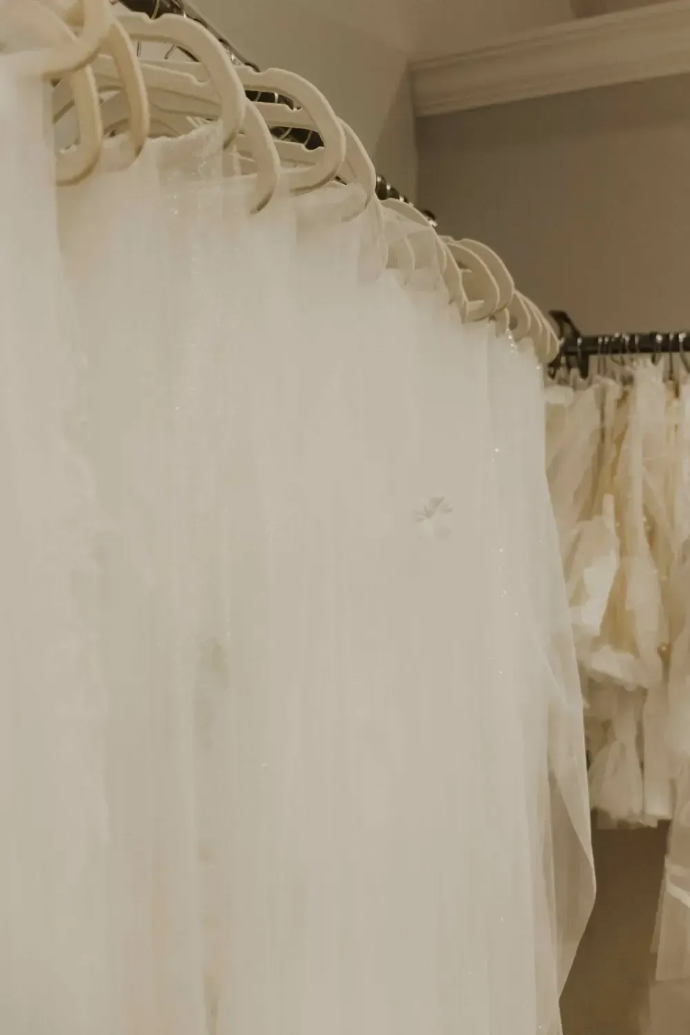 White tulle veils hanging on a rack in a bridal shop.