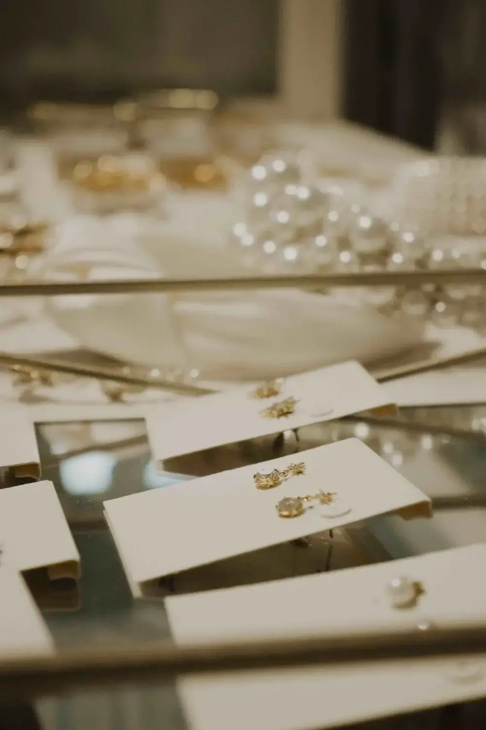 Jewelry display case with earrings on white cards, pearls, and other gold accessories.