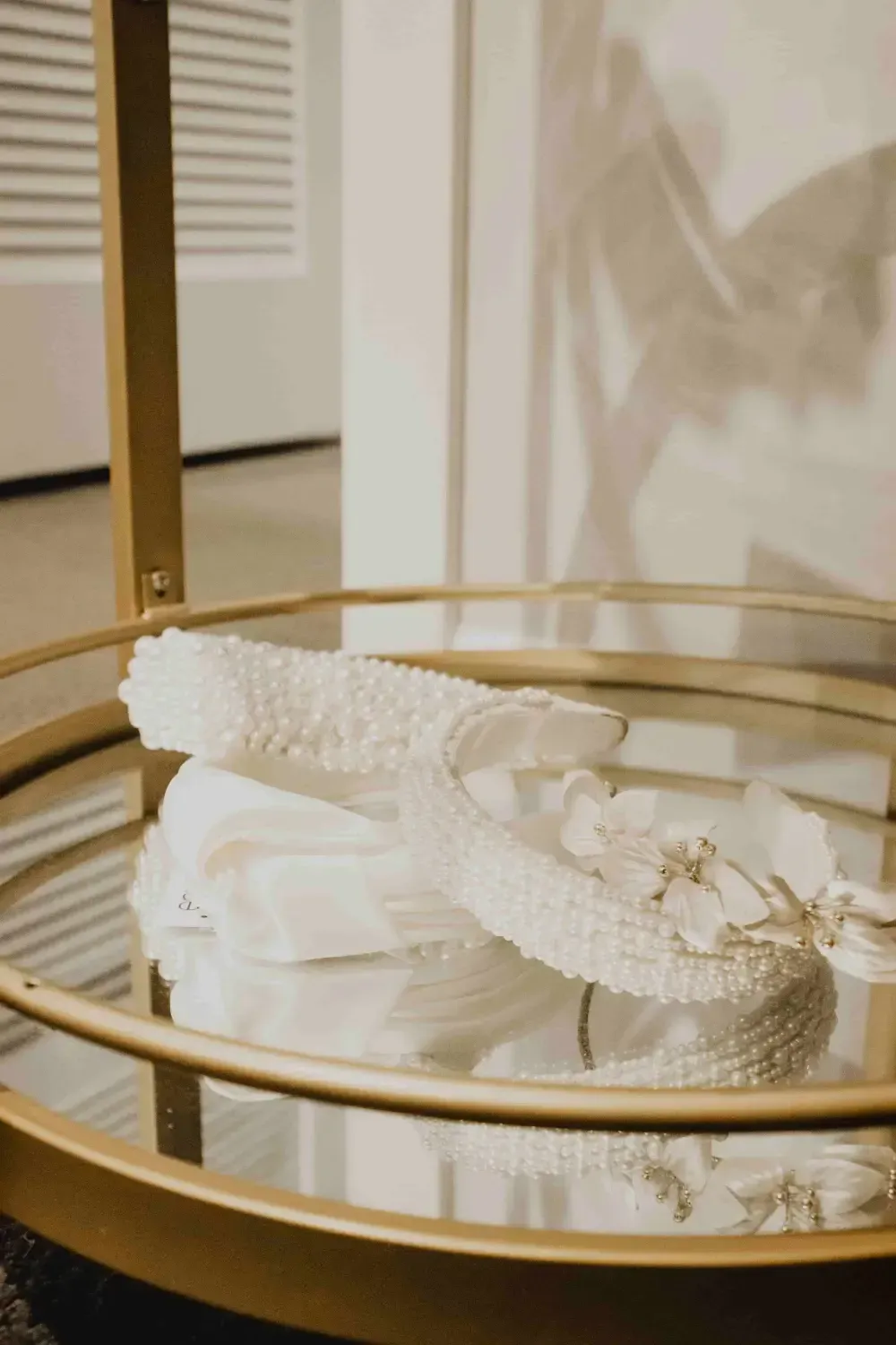 White accessories on a gold-rimmed mirrored tray, set against a white wall.