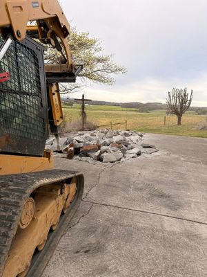 Bulldozer clearing rubble on a rural roadside with fields in the background