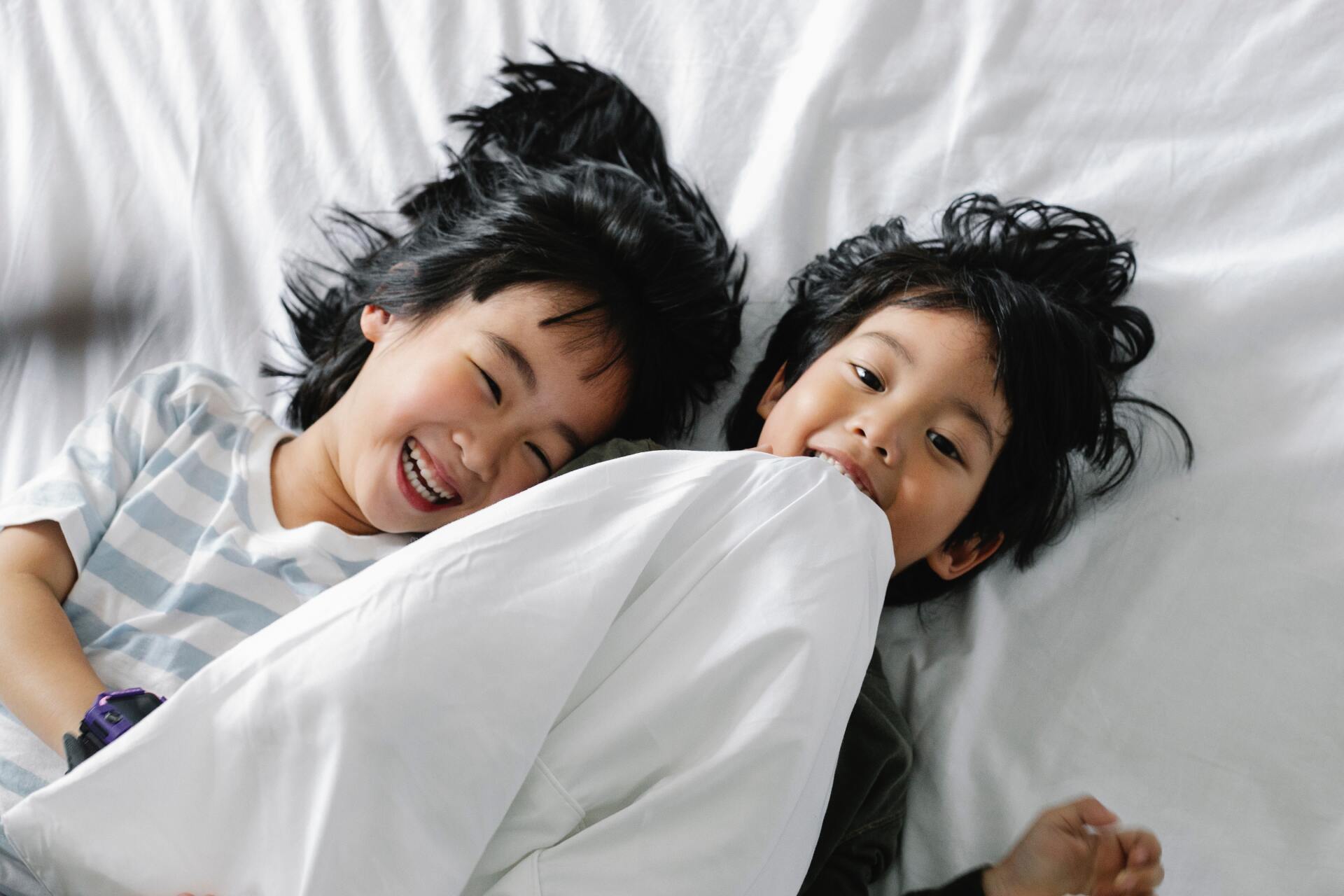 2 brothers laying on a bed laughing