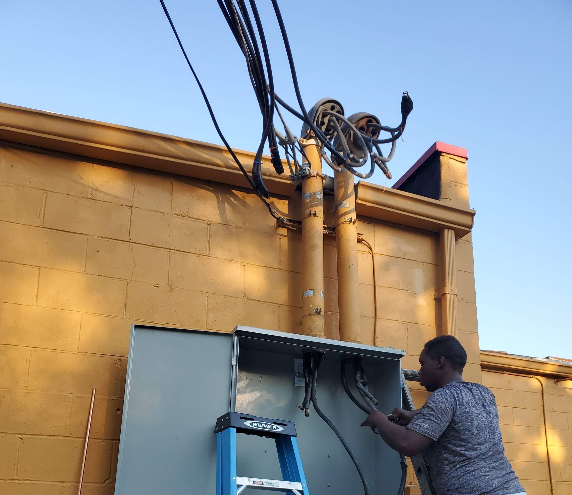 A man on a ladder working on a box on the side of a building