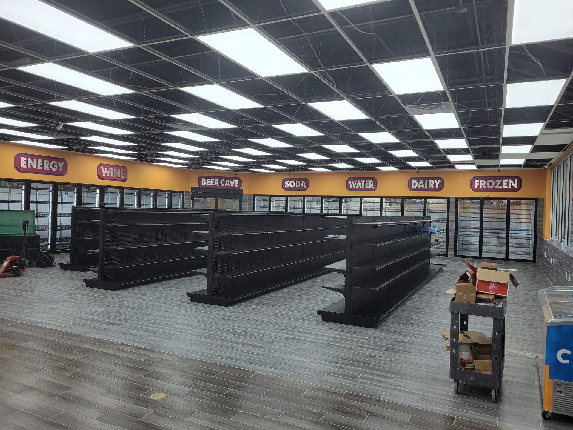 The inside of a grocery store with empty shelves and refrigerators.