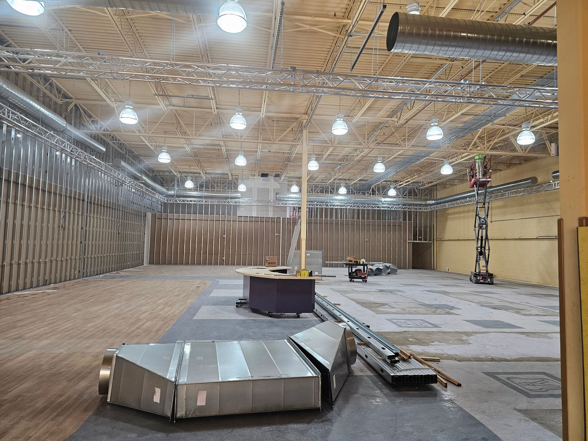 A large empty room with a lot of ducts hanging from the ceiling.