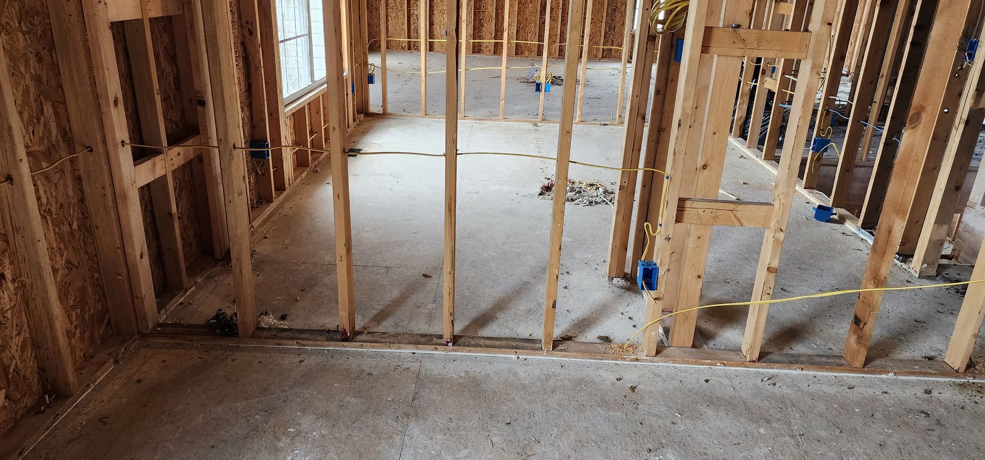 A room in a house under construction with wooden beams and a concrete floor.