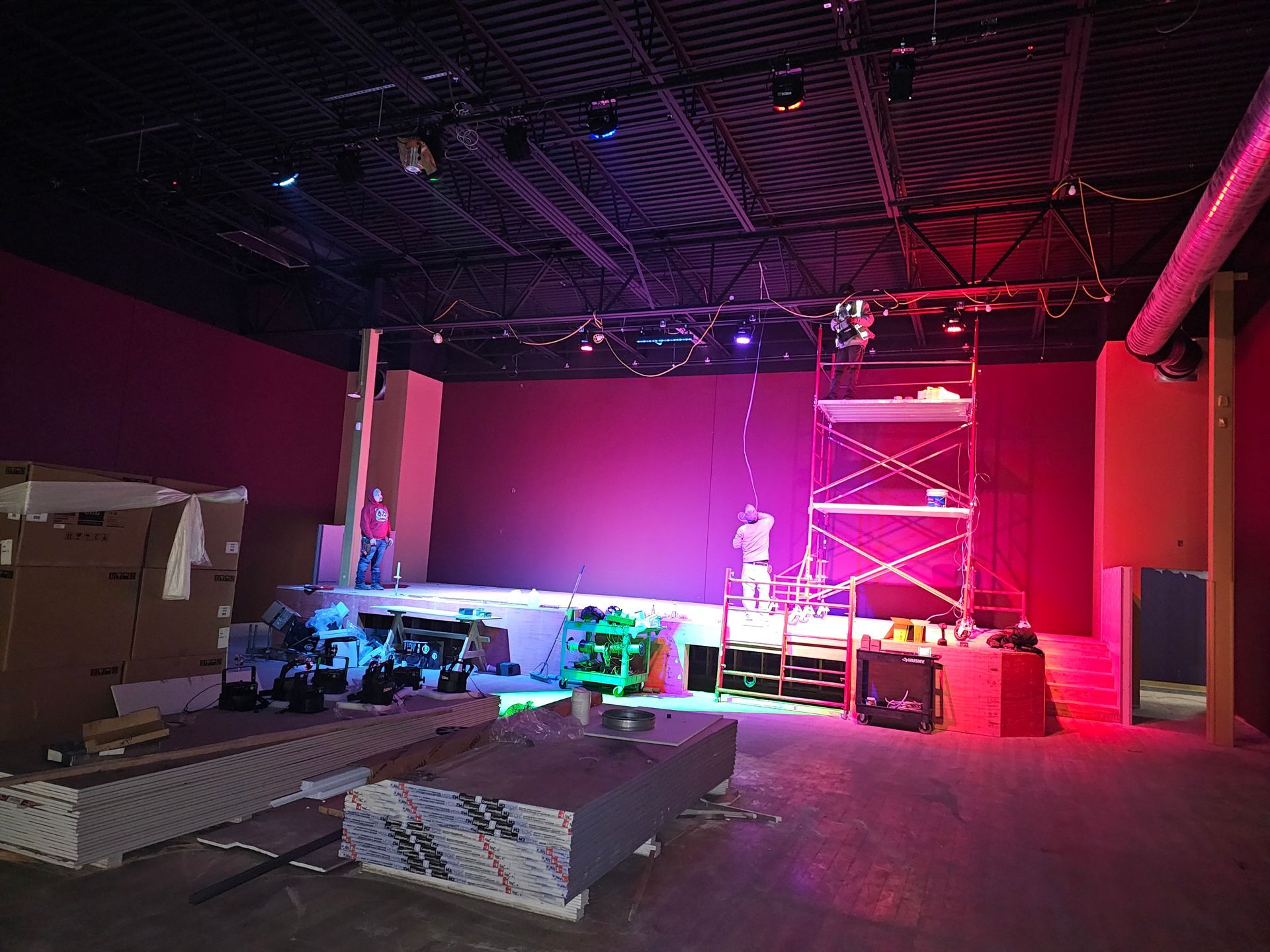 A stage is being built in a large room with purple lights.