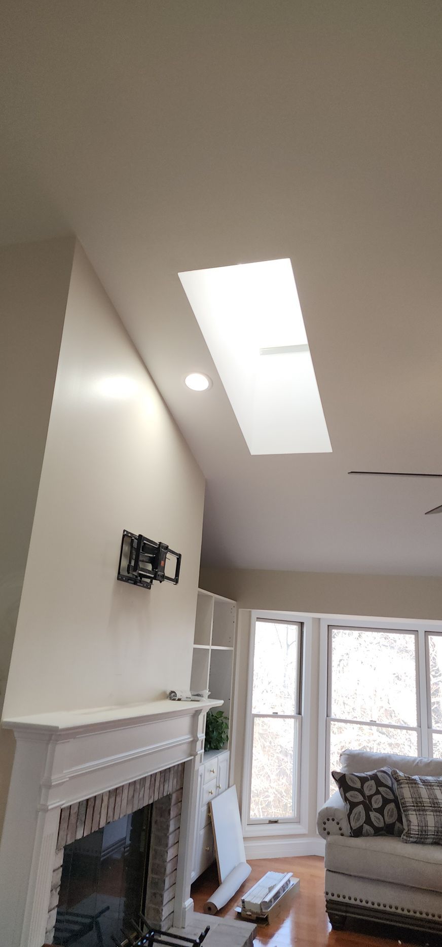 A living room with a fireplace and a skylight in the ceiling.