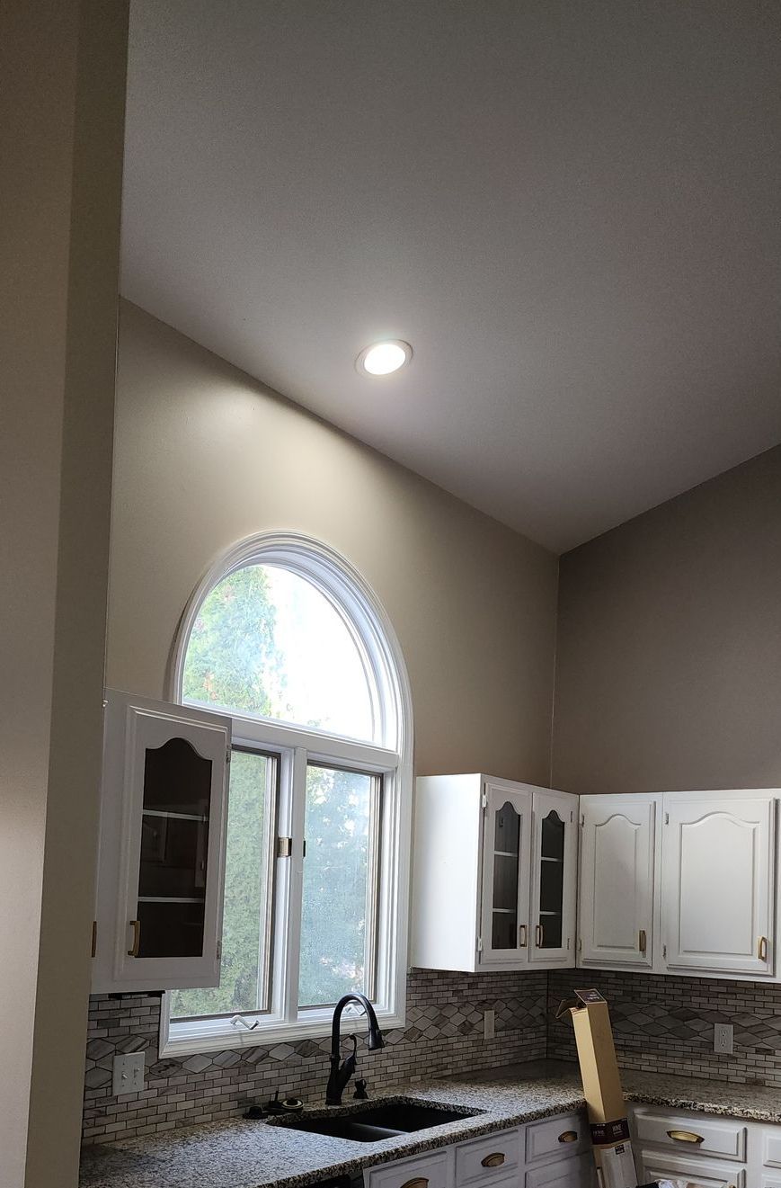 A kitchen with a sink , cabinets , and a window.