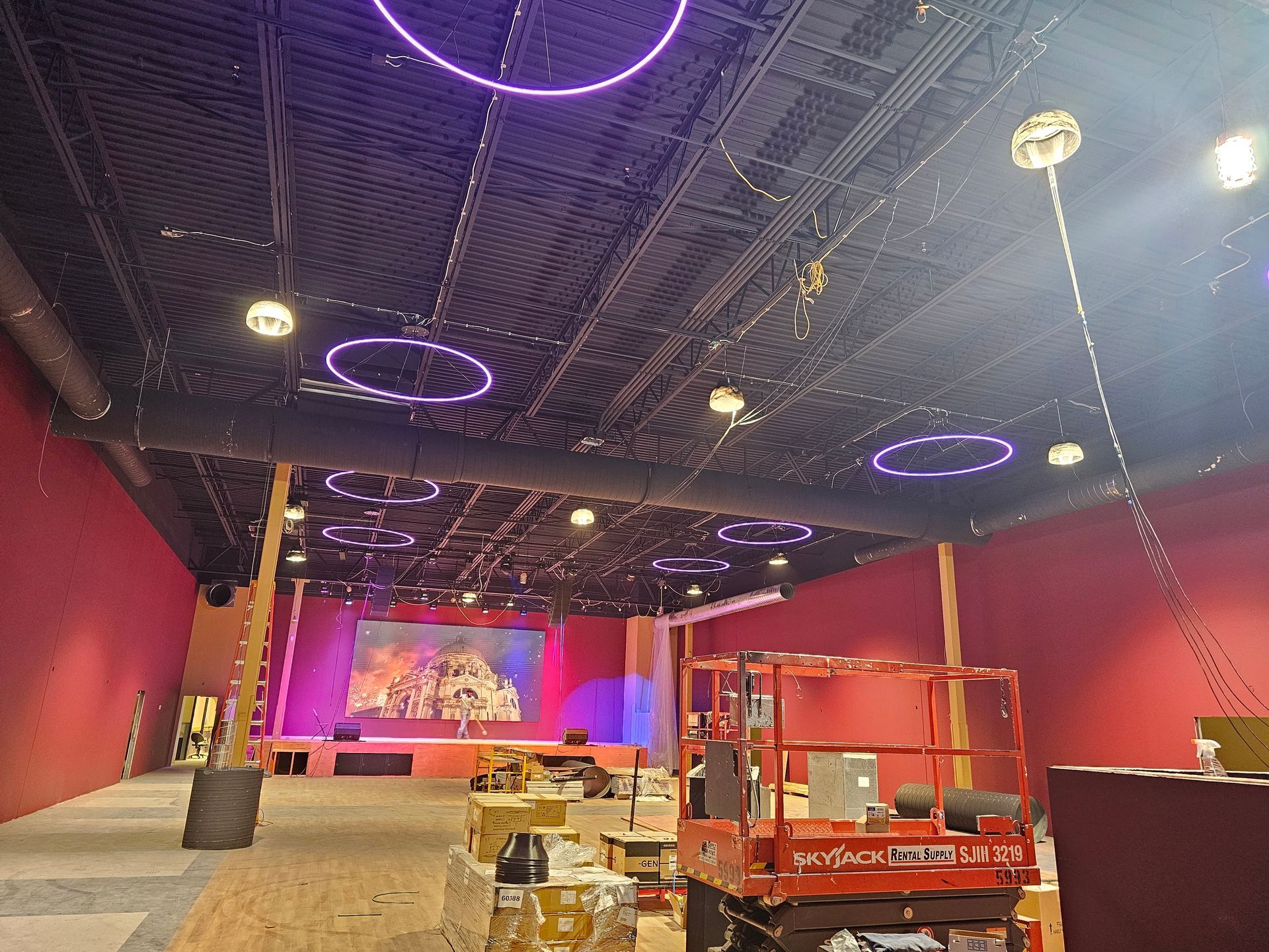 A large room with a stage and neon lights on the ceiling.