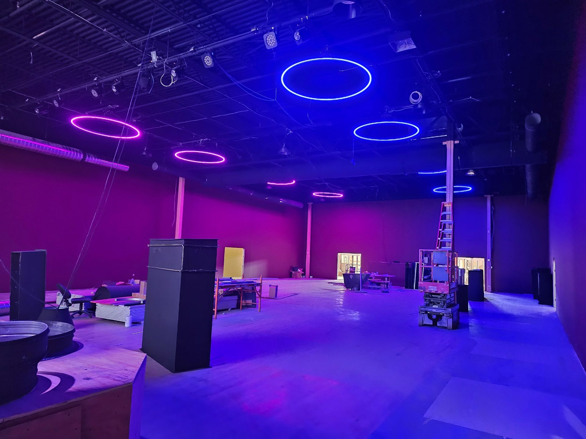 A large empty room with purple lights on the ceiling.