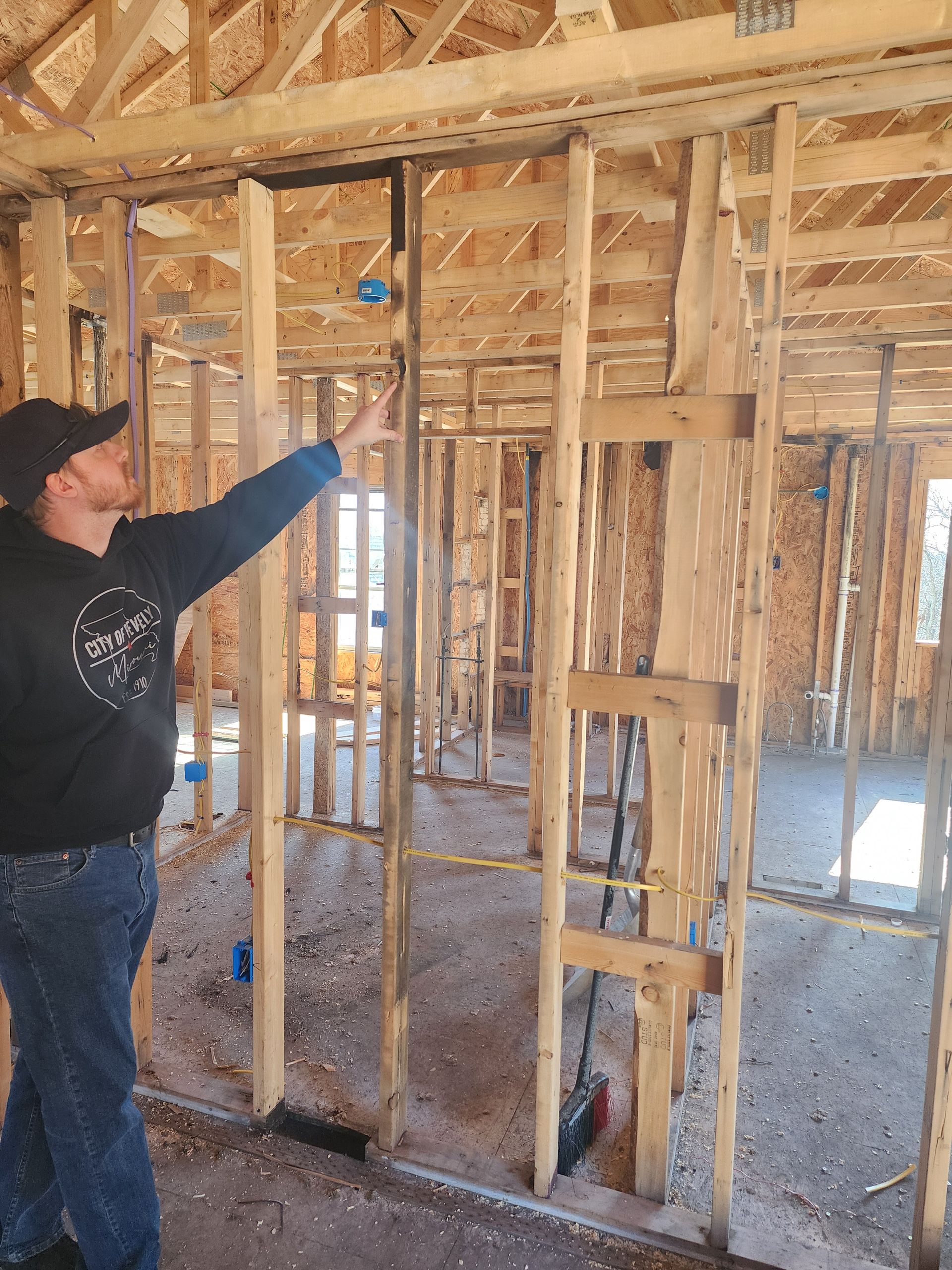A man is measuring a wall in a house under construction