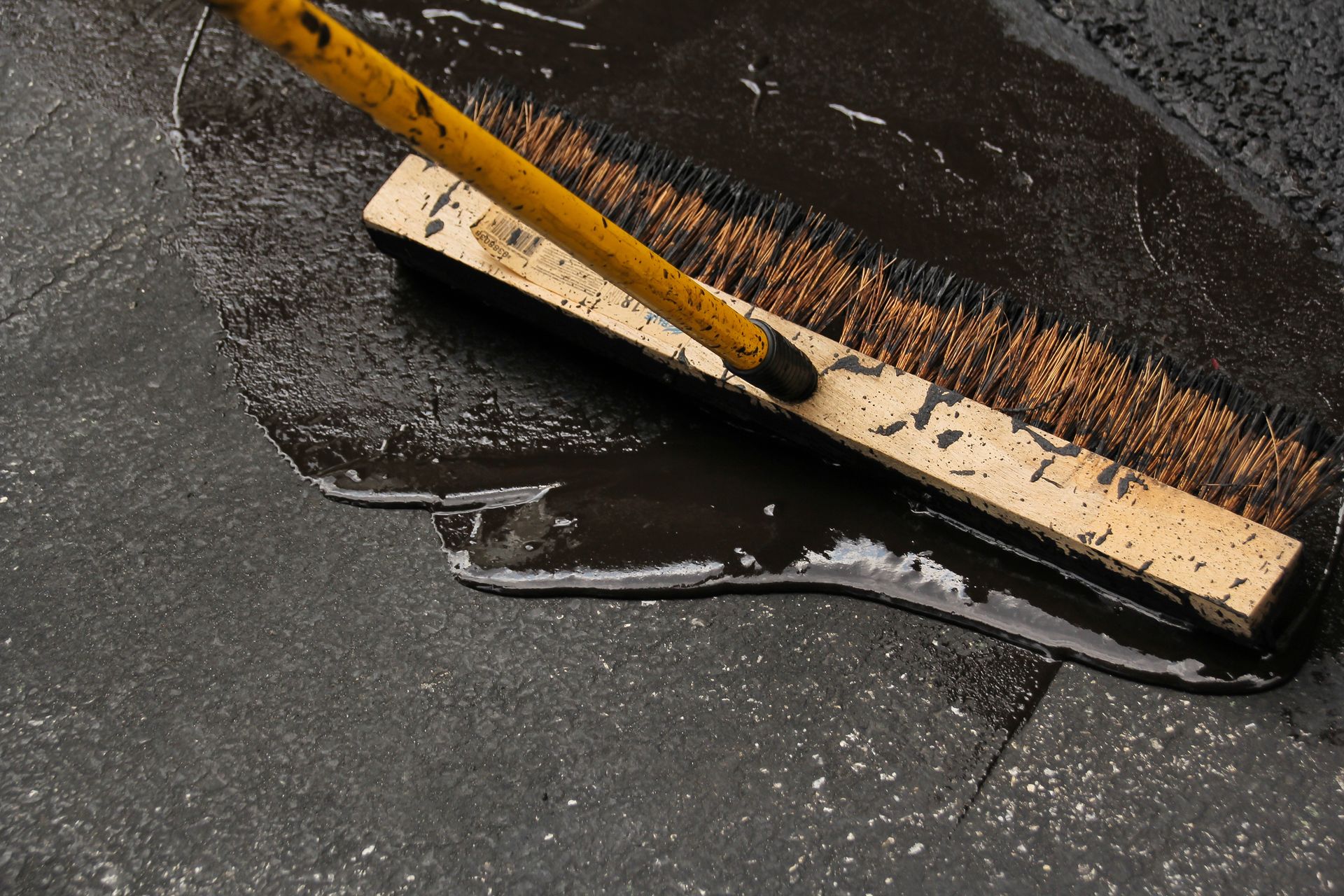 A yellow broom is being used to clean a dirty floor