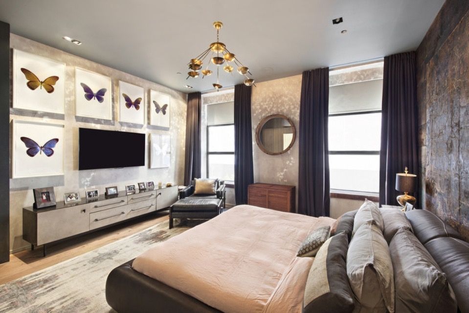 Elegant bedroom with butterfly art above the TV. Includes a bed, chair, and dark curtains.